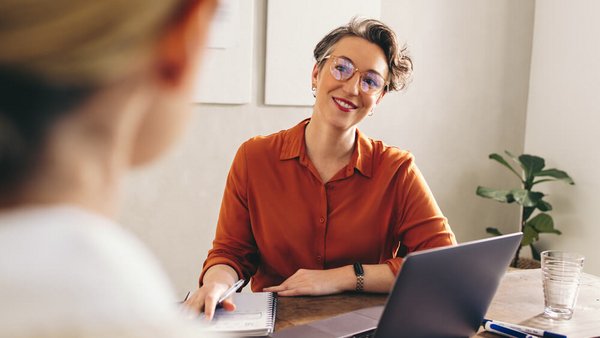 Zwei Frauen sitzen gegenüber an einem Schreibtisch und führen ein Beratungsgespräch